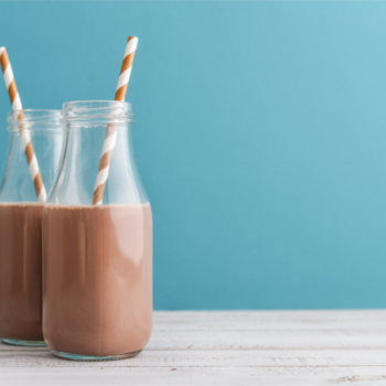 Image of chocolate milk in glass bottles with straws.