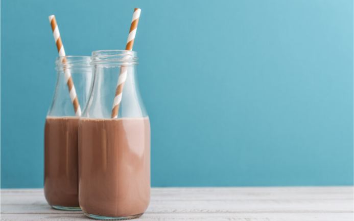 Image of chocolate milk in glass bottles with straws.