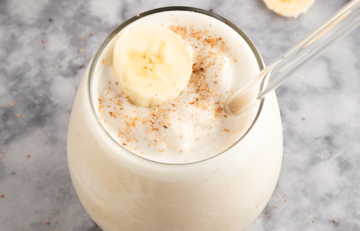 Banana licuado in a glass topped with banana and cinnamon.