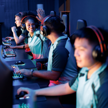 Two happy esports team members celebrating success while giving high five to each other in gaming club