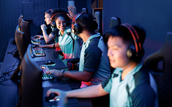 Two happy esports team members celebrating success while giving high five to each other in gaming club