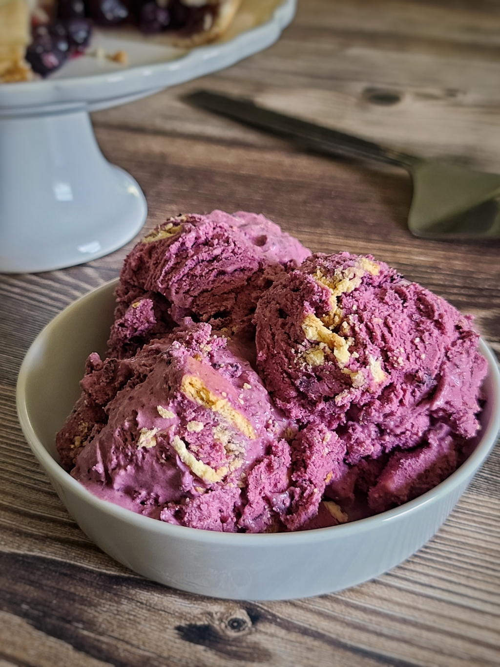 Bowl of blueberry pie ice cream on a wooden table.
