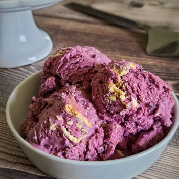 Bowl of blueberry pie ice cream on a wooden table.