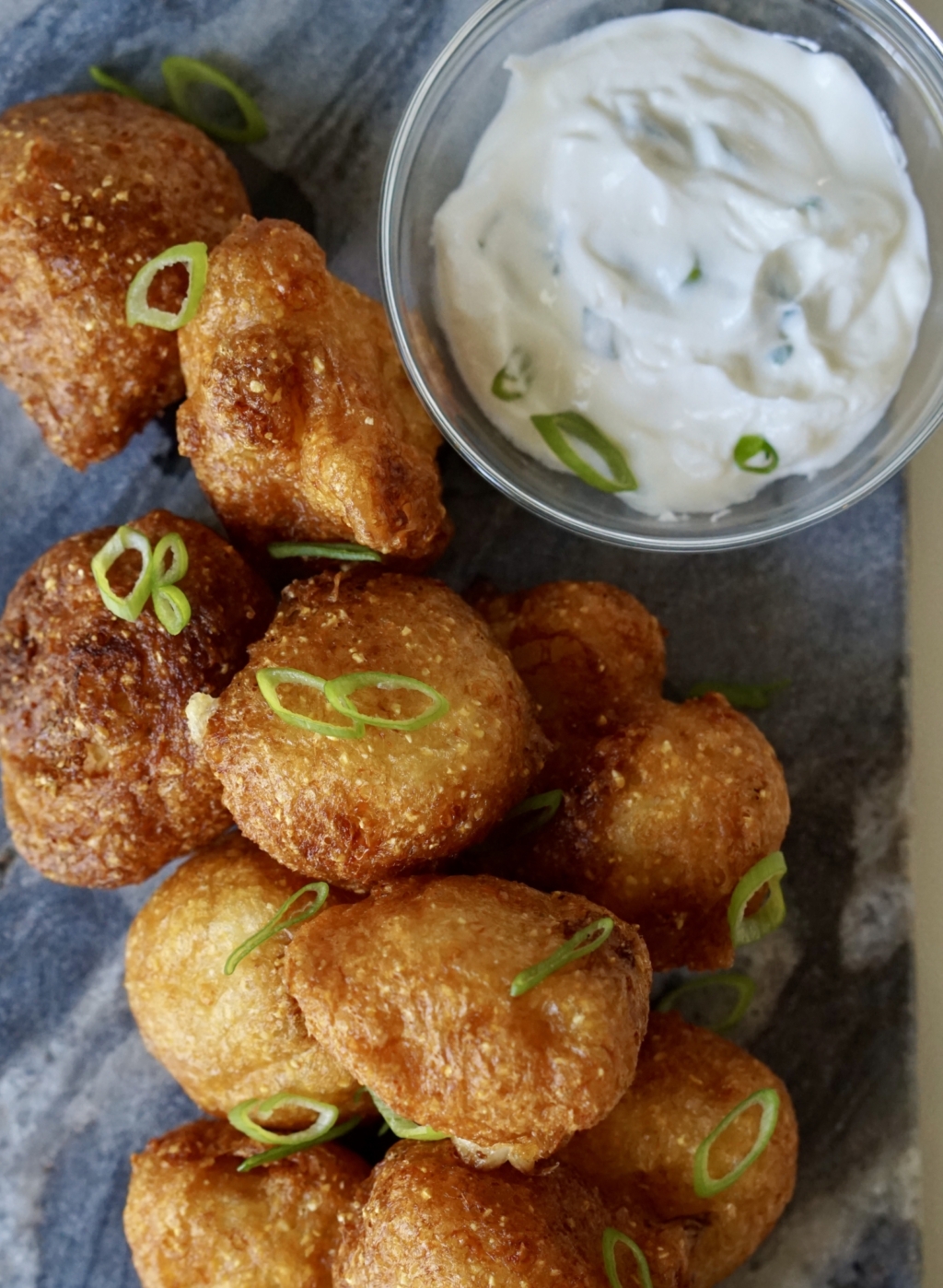 Buttermilk friend cauliflower with a side of yogurt sauce on a marble countertop.