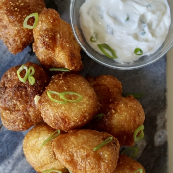 Buttermilk friend cauliflower with a side of yogurt sauce on a marble countertop.
