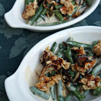 Two dishes of modern green bean casserole on a table cloth.