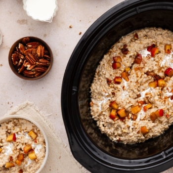 Slow cooker with apple cinnamon steel cut oats with pecans, brown sugar, and peaches.