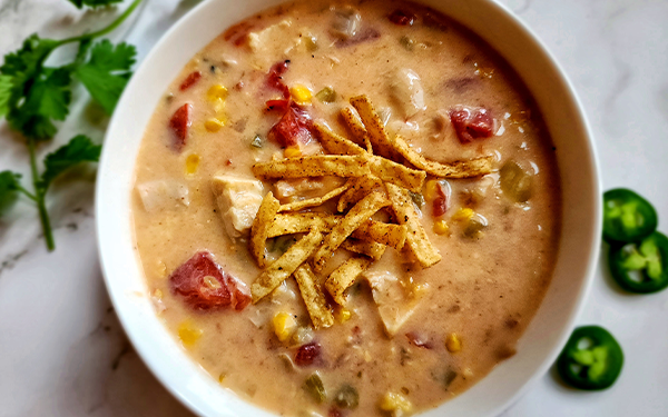 Overhead image of cheesy chicken enchilada soup topped with tortilla chip strips.