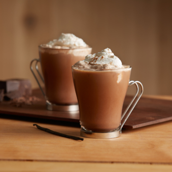 Image of two chocolate chai lattes topped with whipped cream.