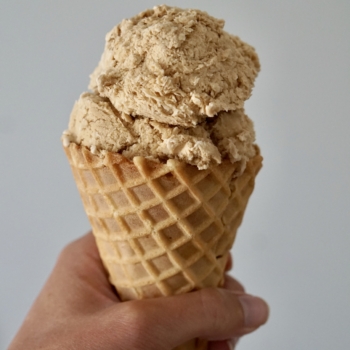 Image of a hand holding a waffle cone with a scoop of coffee ice cream.