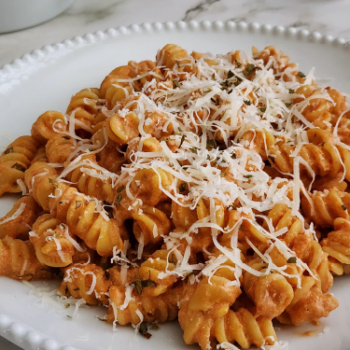 Image of cottage cheese and tomato pasta on a plate with shredded parmesan on top.