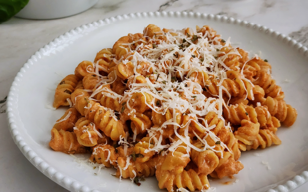 Image of cottage cheese and tomato pasta on a plate with shredded parmesan on top.