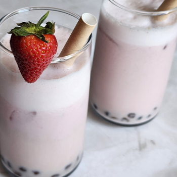 Image of two creamy strawberry boba teas in glasses.
