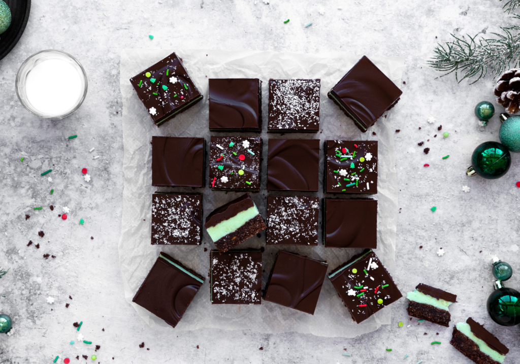 Image of Creme de Menthe bars surrounded by a glass of milk and festive holiday decorations.