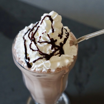 Image of chocolate milkshake with whipped cream and chocolate syrup drizzle.