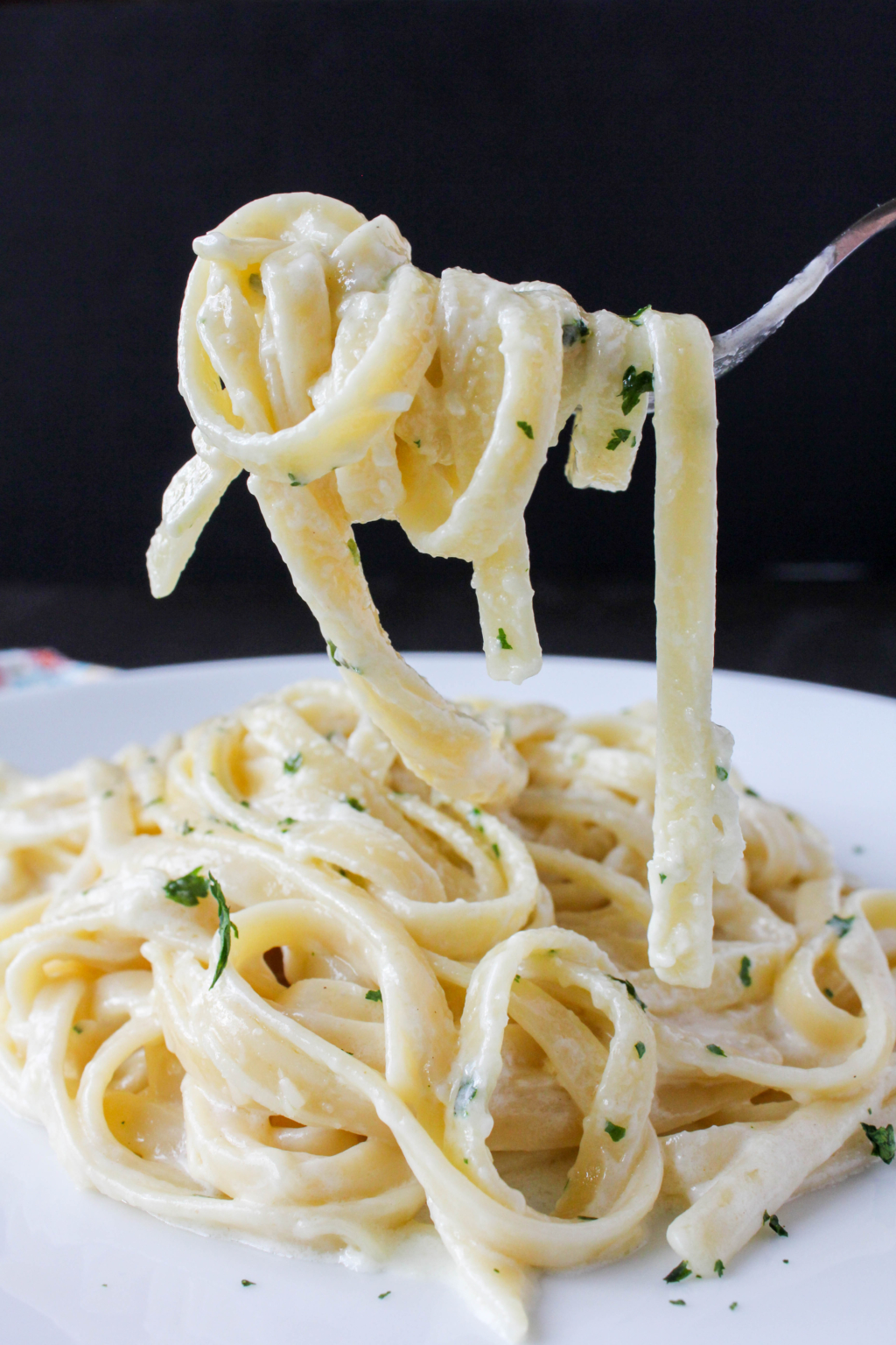 Image of a fettuccine Alfredo noodles twirled around a fork.