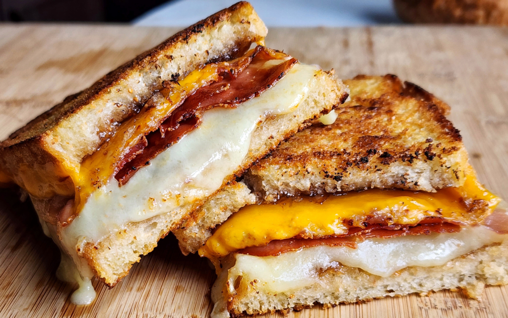 Image of a halved fig and prosciutto grilled cheese sandwich.