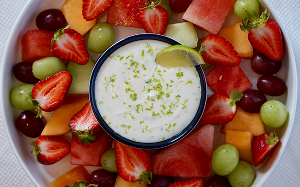 Overhead image of fresh fruit surrounding a bowl of creamy lime dip.