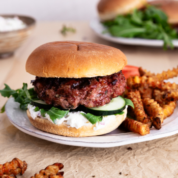 Image of a Greek Cheese Burger on a plate with crinkle fries.