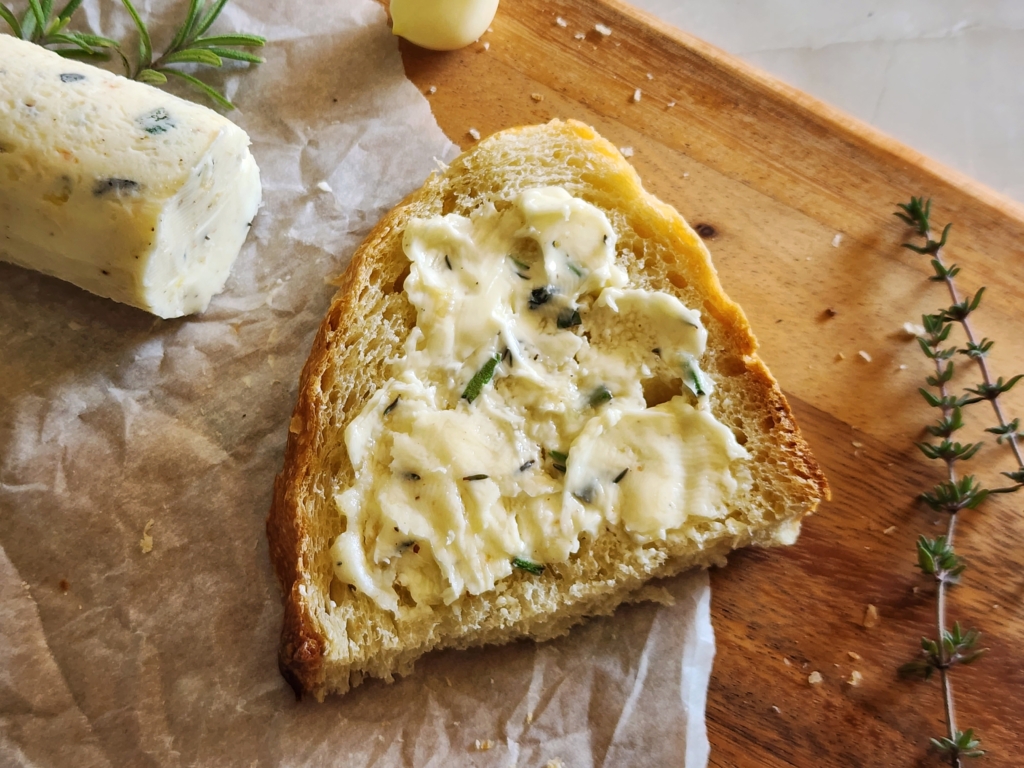 Image of herbed butter spread on a slice of bread.