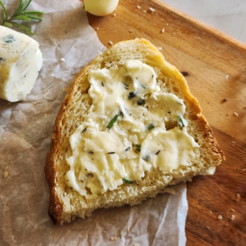 Image of herbed butter spread on a slice of bread.