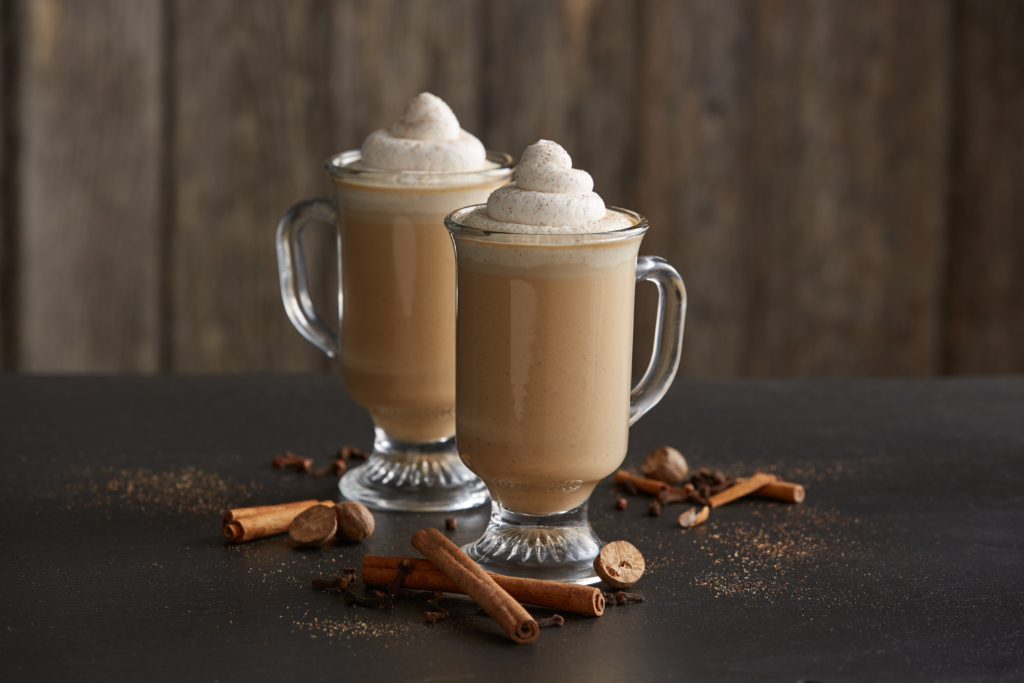 Two pumpkin lattes in glasses topped with whipped cream