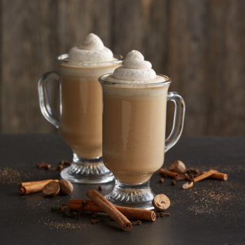 Two pumpkin lattes in glasses topped with whipped cream