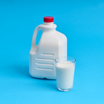Container and glass of lactose free milk on a bright blue background.