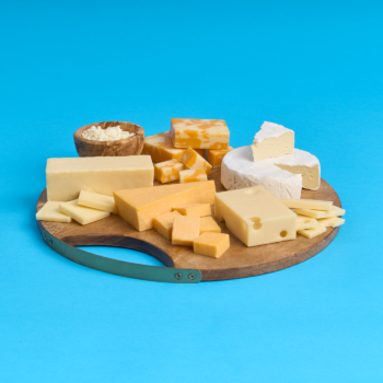 Wooded cheeseboard with brie, bolby, swiss, cheddar, feta, and parmesan on a bright blue background.