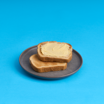 Gray plate with two slices of buttered toast on a bright blue background.