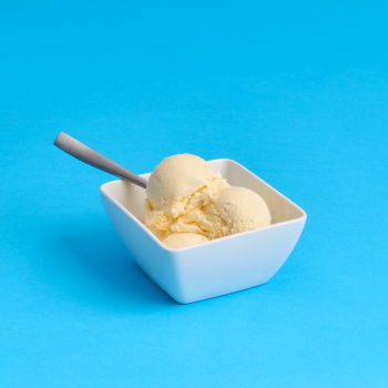 Bowl of vanilla ice cream scoops on a bright blue background.