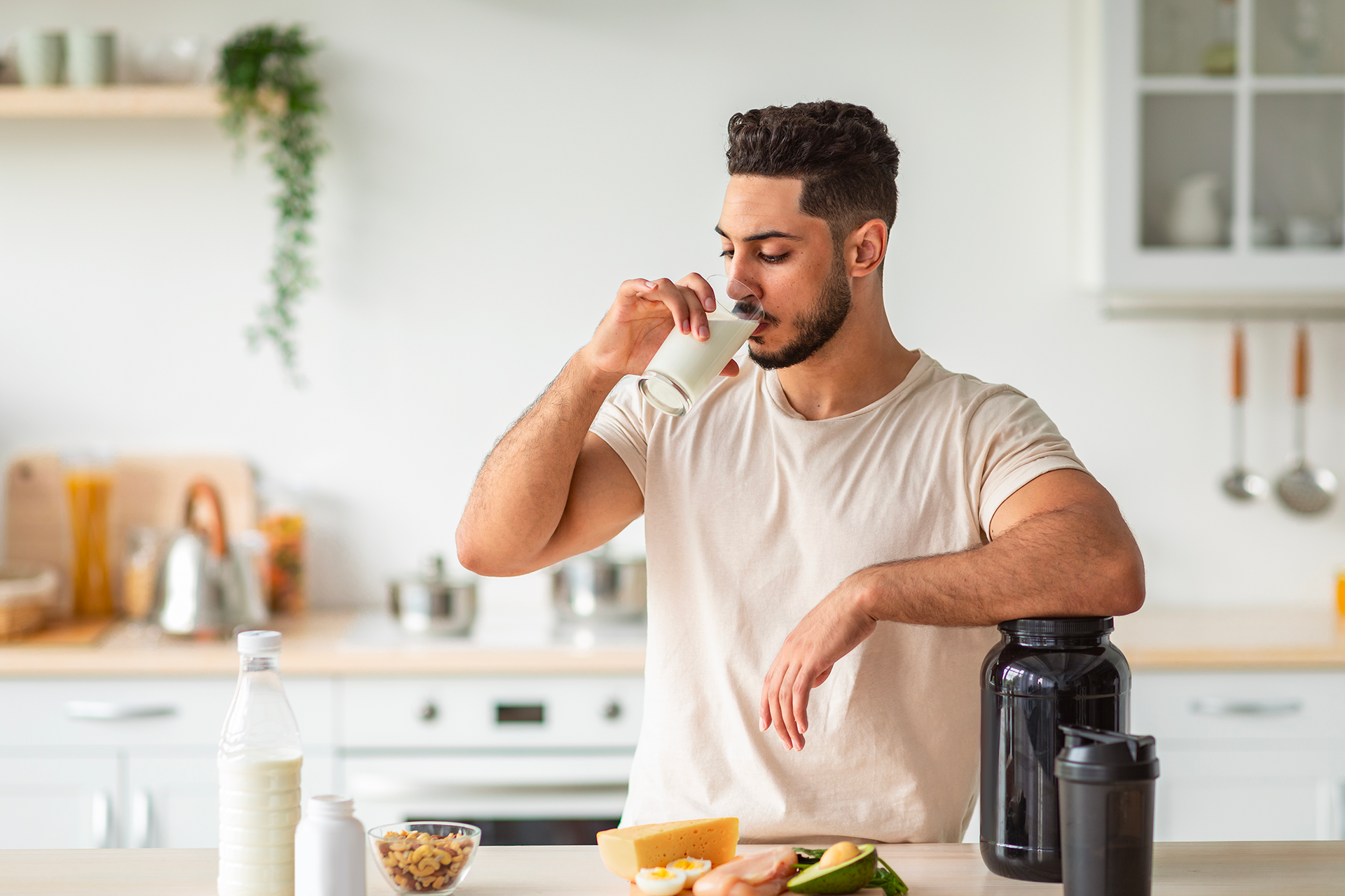 Young professional male at home drinking a glass of white milk in the kitchen.