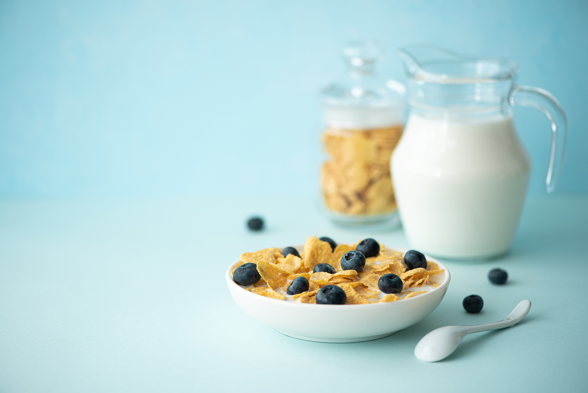 Bowl of cereal and container of white milk on a blue background.