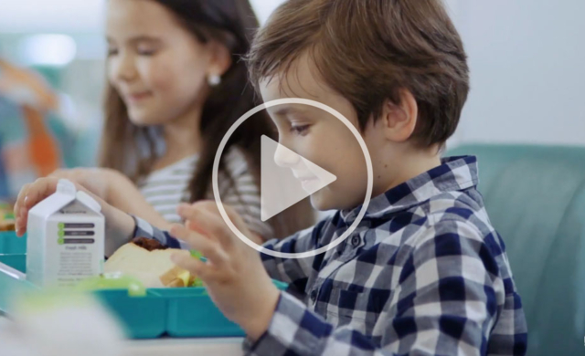 Image of a young kid eating a school lunch in a cafeteria.