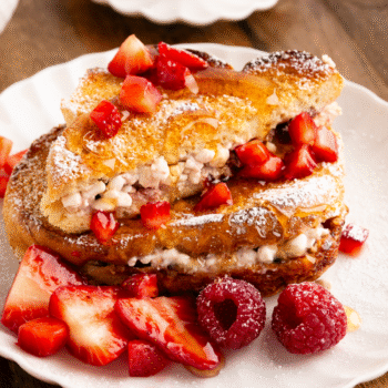 Image of baked stuffed french toast on a plate with berries and syrup.
