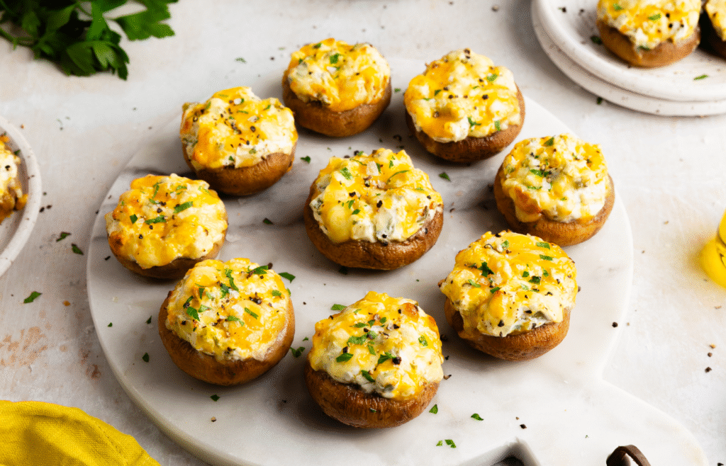 Image of several cheesy stuffed mushrooms on a plate.