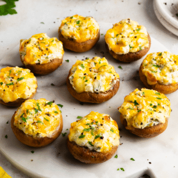 Image of several cheesy stuffed mushrooms on a plate.